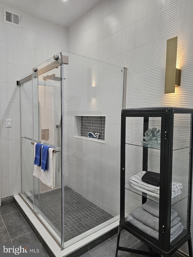 bathroom featuring a shower with shower door and tile flooring