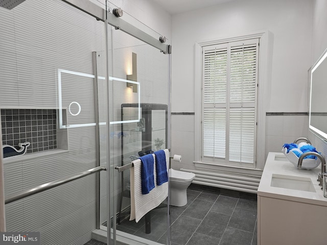 bathroom featuring vanity with extensive cabinet space, double sink, toilet, and tile flooring