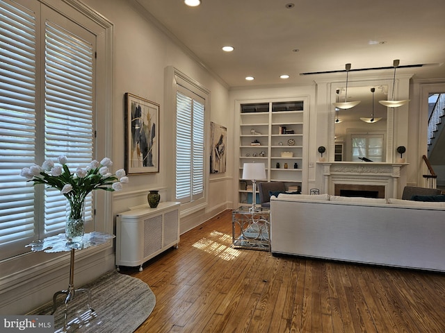 living room featuring built in features, crown molding, radiator, and dark wood-type flooring