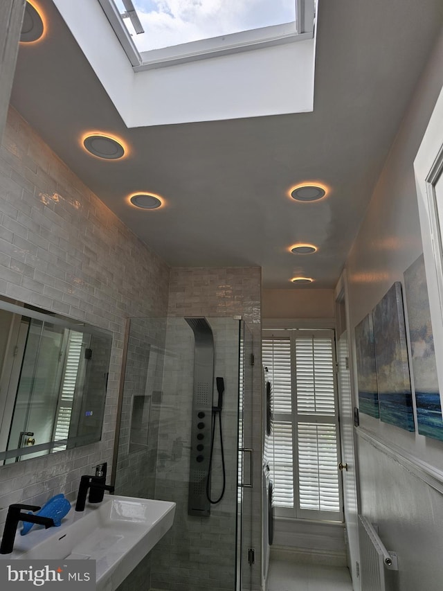 bathroom with a skylight, sink, and a tile shower