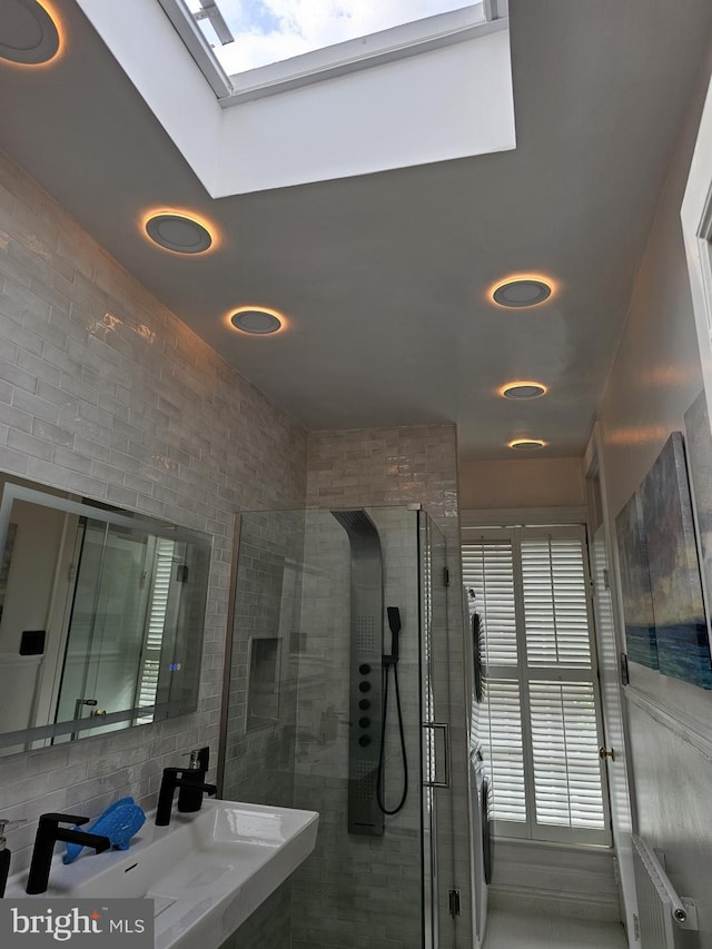 bathroom featuring a wealth of natural light, a skylight, walk in shower, and sink