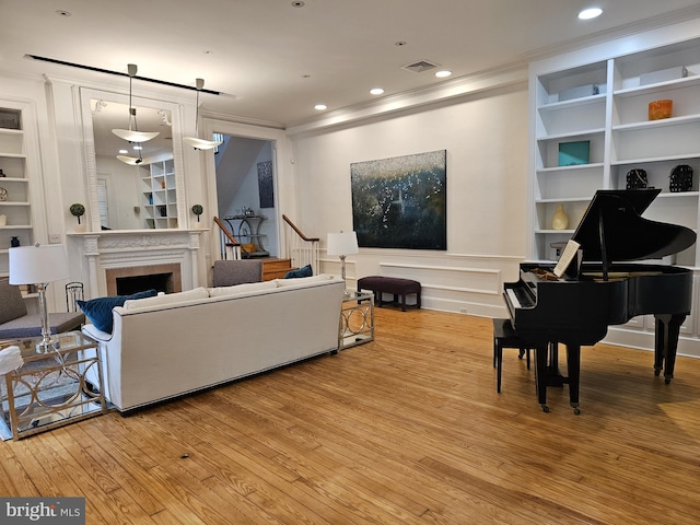 living room featuring light hardwood / wood-style floors, built in features, and crown molding