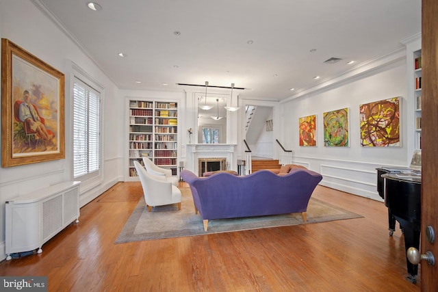 living room with hardwood / wood-style floors, radiator, built in shelves, and crown molding