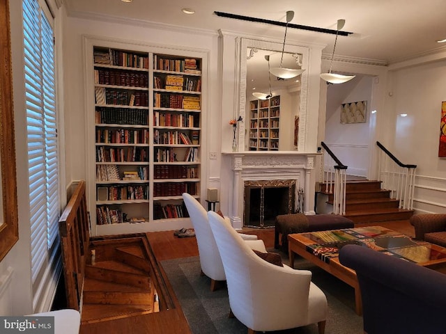 living room with a fireplace, hardwood / wood-style floors, built in features, and ornamental molding