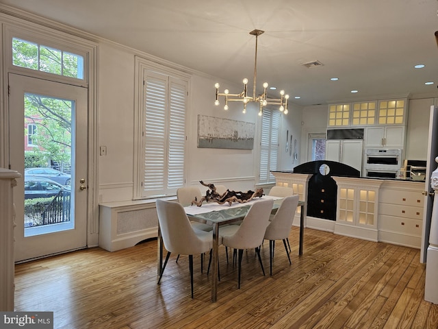 dining room featuring an inviting chandelier, light hardwood / wood-style floors, and crown molding