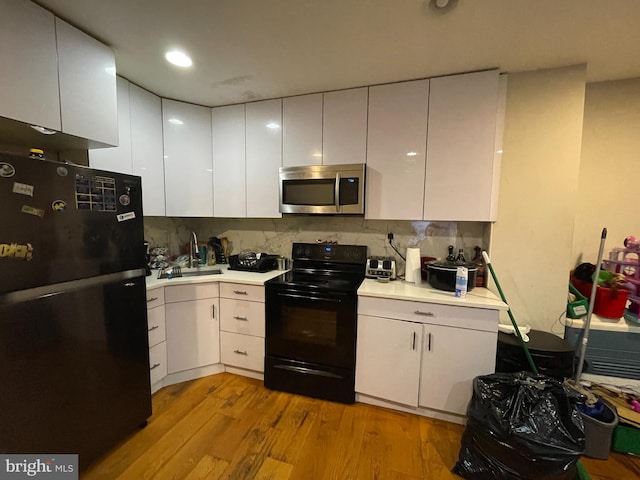 kitchen featuring black appliances, light hardwood / wood-style flooring, tasteful backsplash, sink, and white cabinets