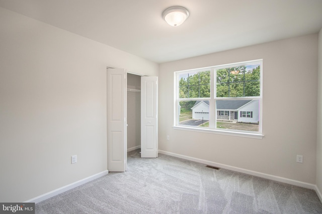 unfurnished bedroom with light carpet and a closet