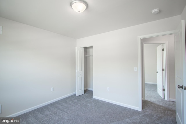 unfurnished bedroom with dark carpet and a closet