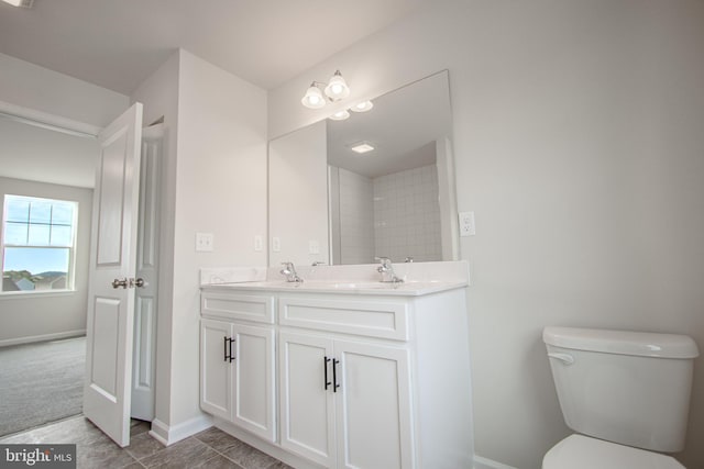 bathroom with toilet, vanity, and tile patterned flooring