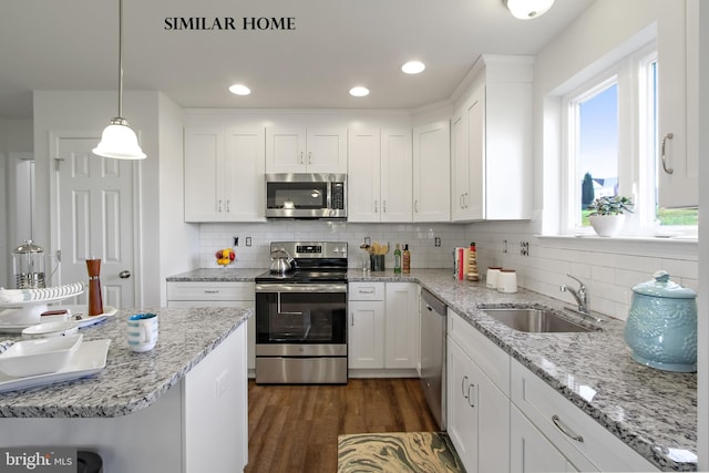 kitchen featuring white cabinets, hanging light fixtures, dark wood-type flooring, sink, and stainless steel appliances