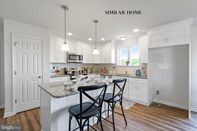 kitchen featuring light stone countertops, a kitchen island, stainless steel appliances, white cabinets, and dark hardwood / wood-style floors