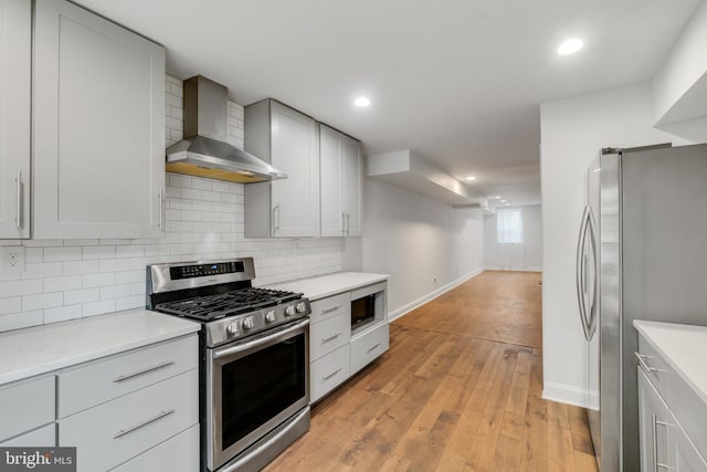 kitchen featuring light hardwood / wood-style flooring, stainless steel appliances, and wall chimney range hood