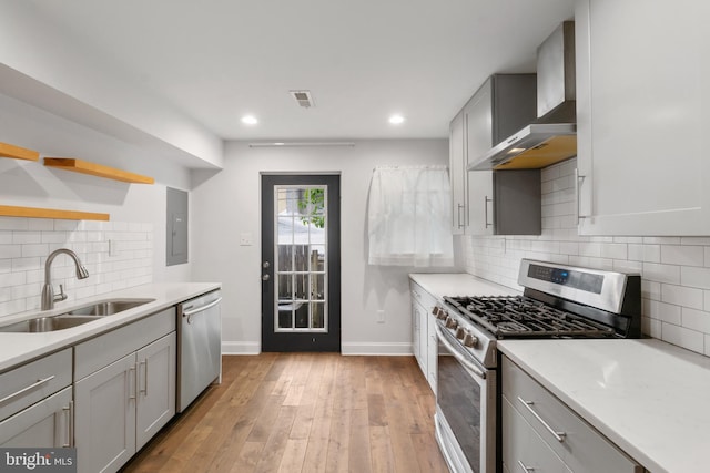 kitchen with appliances with stainless steel finishes, sink, light hardwood / wood-style floors, backsplash, and gray cabinets