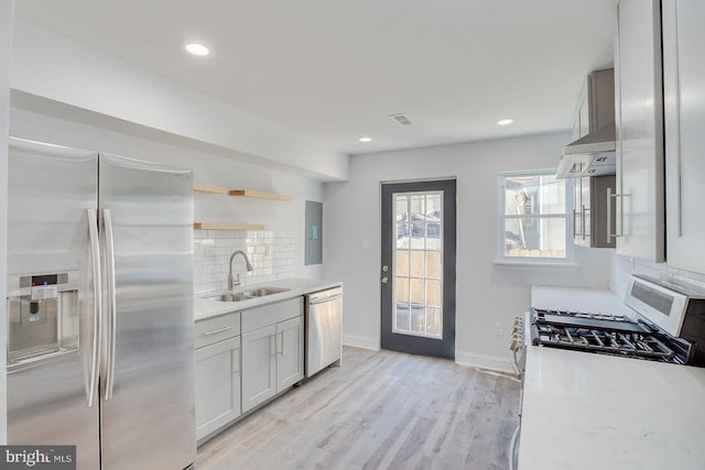 kitchen with tasteful backsplash, stainless steel appliances, sink, and light wood-type flooring