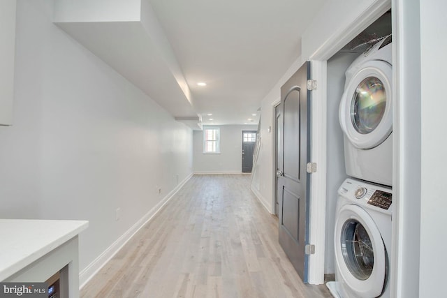 clothes washing area with light hardwood / wood-style floors and stacked washer and dryer