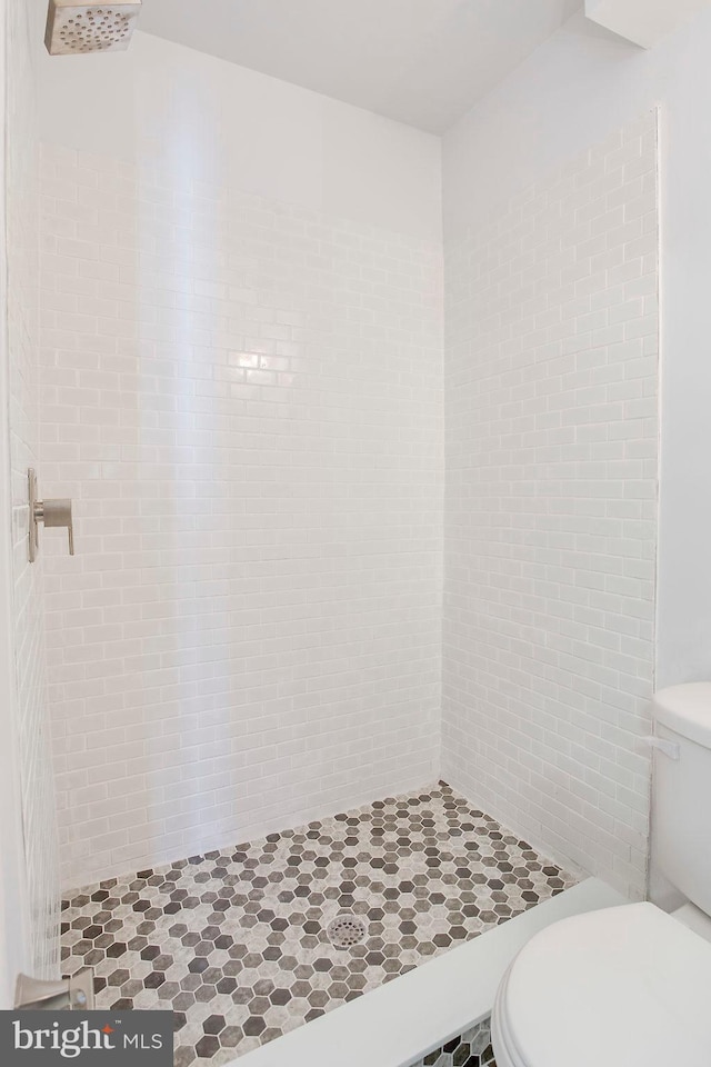 bathroom with tiled shower and toilet