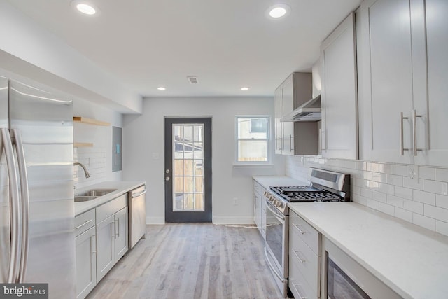 kitchen with backsplash, sink, stainless steel appliances, and light wood-type flooring