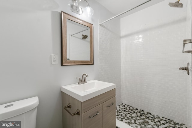 bathroom with toilet, vanity, and a tile shower