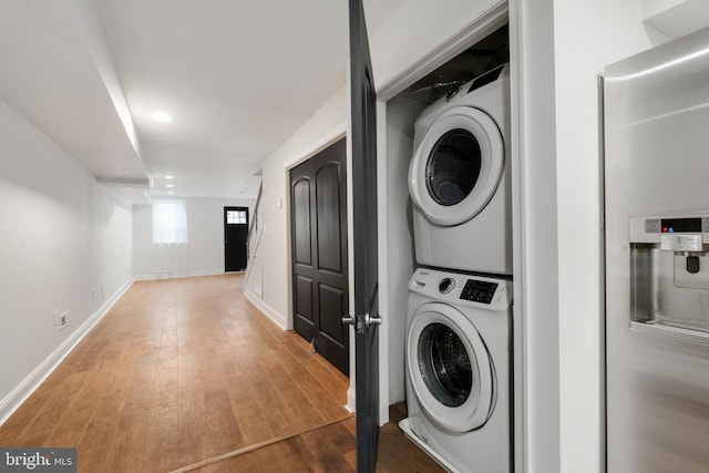 laundry area with wood-type flooring and stacked washing maching and dryer