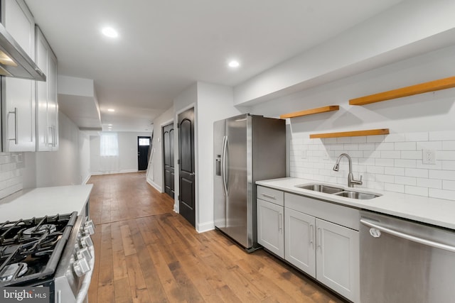 kitchen featuring premium range hood, stainless steel appliances, tasteful backsplash, sink, and light wood-type flooring