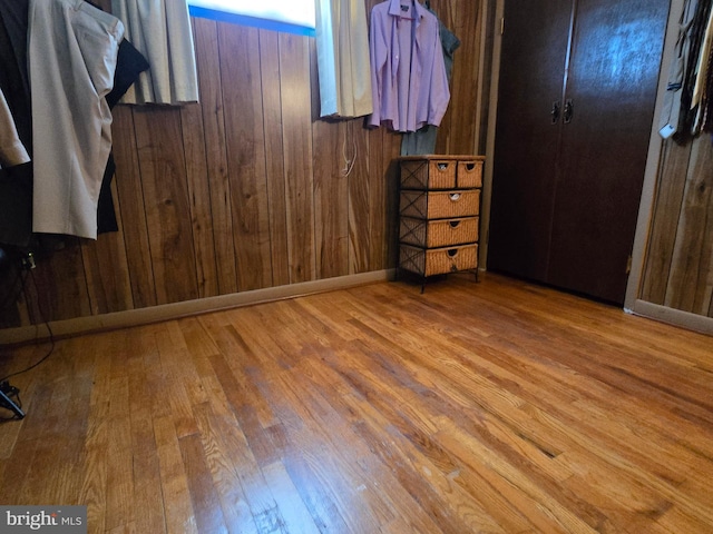 unfurnished bedroom featuring hardwood / wood-style flooring and wooden walls