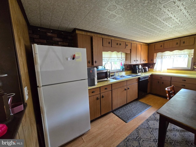 kitchen featuring white refrigerator, sink, black dishwasher, and light wood-type flooring