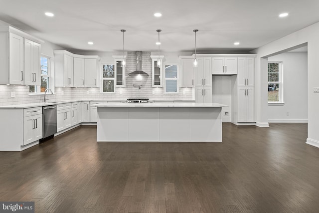 kitchen featuring white cabinetry, a center island, pendant lighting, and wall chimney range hood