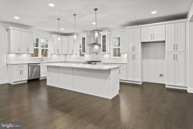 kitchen featuring appliances with stainless steel finishes, wall chimney range hood, white cabinets, a center island, and dark hardwood / wood-style floors