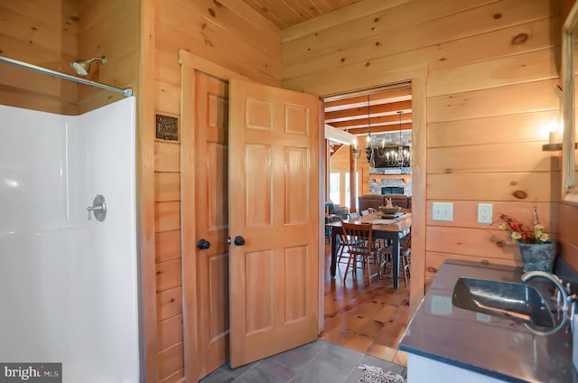 bathroom featuring a shower, sink, and wooden walls