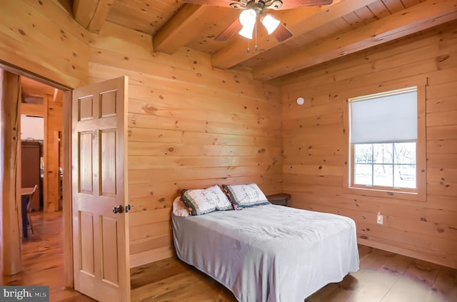 bedroom featuring wood ceiling, wooden walls, light hardwood / wood-style floors, ceiling fan, and beam ceiling