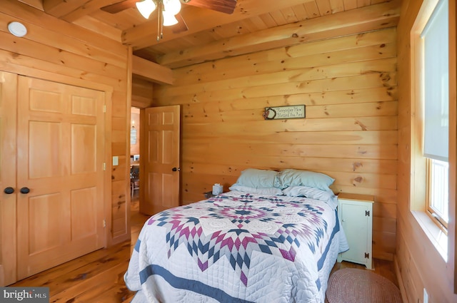 bedroom featuring ceiling fan, light hardwood / wood-style floors, wood ceiling, and wooden walls