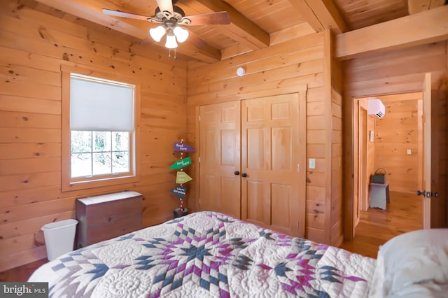 bedroom featuring wood walls, wooden ceiling, ceiling fan, a closet, and beam ceiling