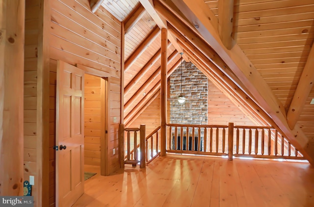 additional living space with hardwood / wood-style flooring, wooden ceiling, wood walls, and lofted ceiling with beams