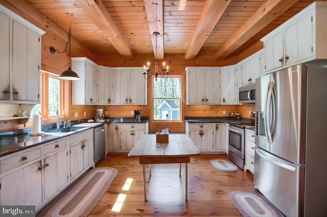 kitchen with stainless steel appliances, white cabinets, hanging light fixtures, light hardwood / wood-style flooring, and a center island