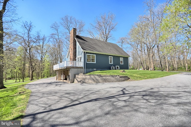 view of side of property with a wooden deck, a lawn, and central air condition unit