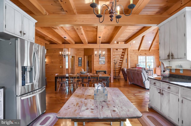 kitchen with decorative light fixtures, wood walls, beamed ceiling, wood ceiling, and stainless steel fridge