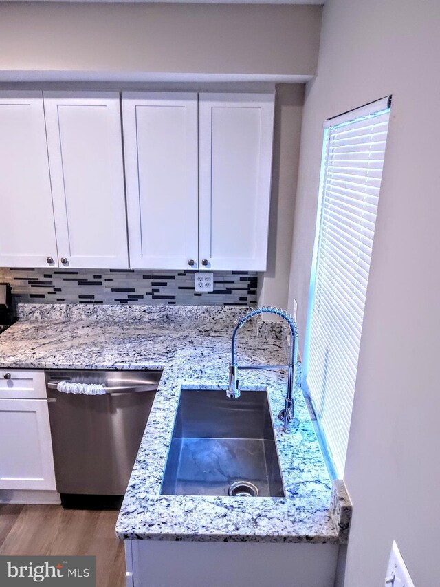 kitchen with backsplash, sink, white cabinets, and stainless steel dishwasher