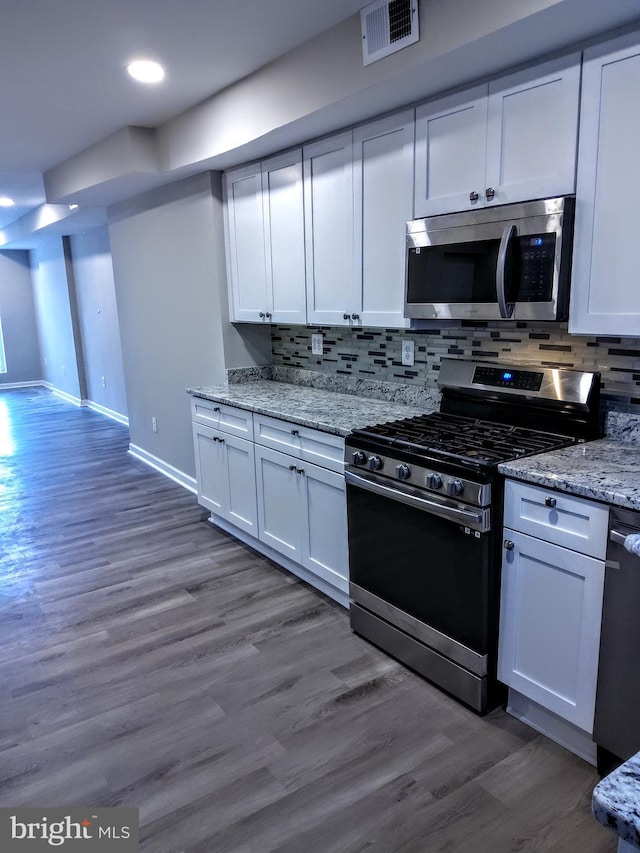 kitchen with backsplash, white cabinets, and stainless steel appliances