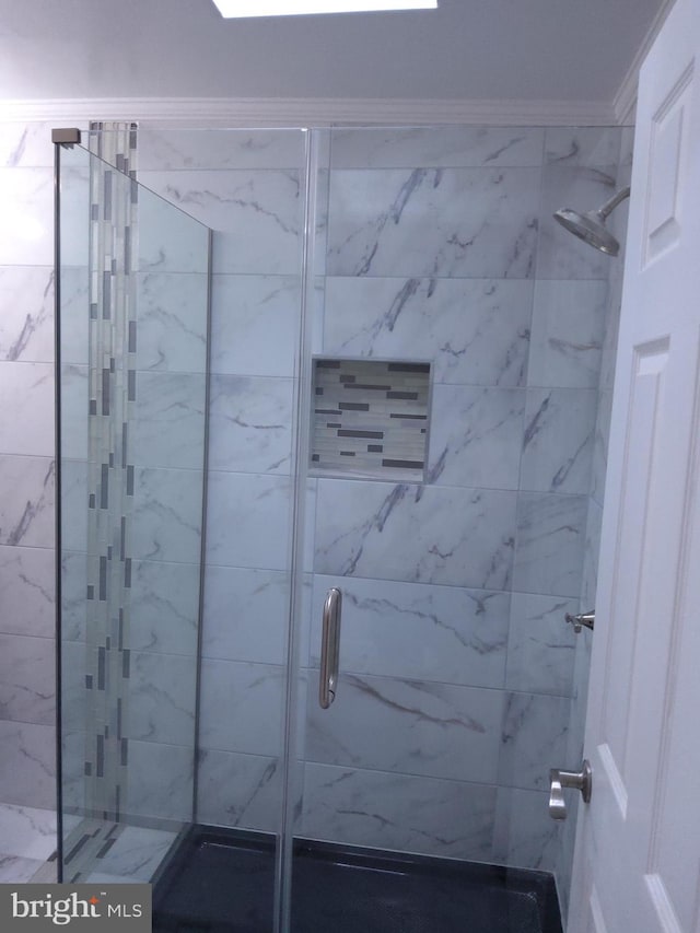 bathroom featuring a shower with door and ornamental molding