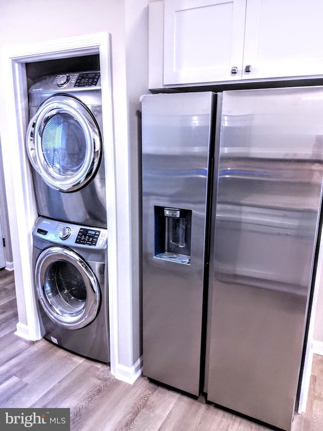 washroom with light hardwood / wood-style flooring and stacked washer / dryer