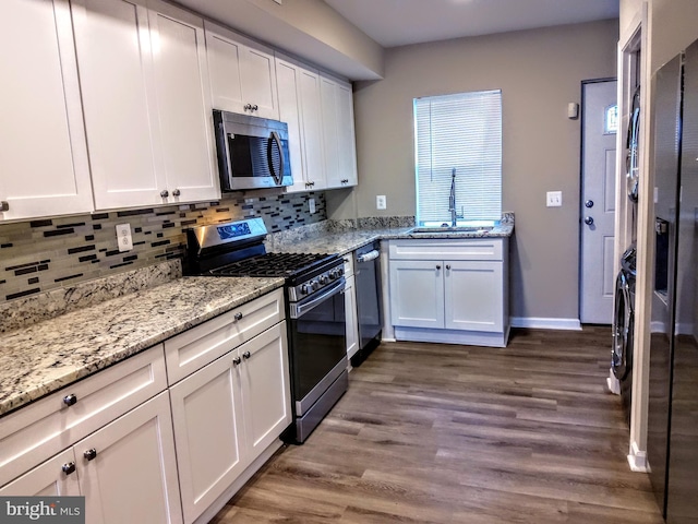 kitchen with decorative backsplash, stainless steel appliances, sink, white cabinets, and hardwood / wood-style floors