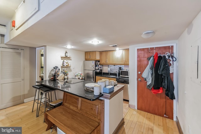 kitchen with a center island, light hardwood / wood-style flooring, stainless steel appliances, and a breakfast bar