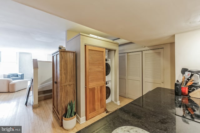 interior space featuring light wood-type flooring, stacked washer and dryer, and dark stone counters