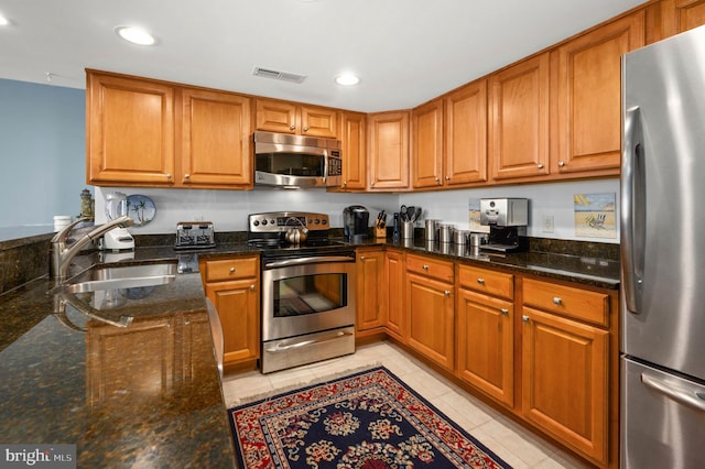 kitchen featuring dark stone countertops, sink, and stainless steel appliances