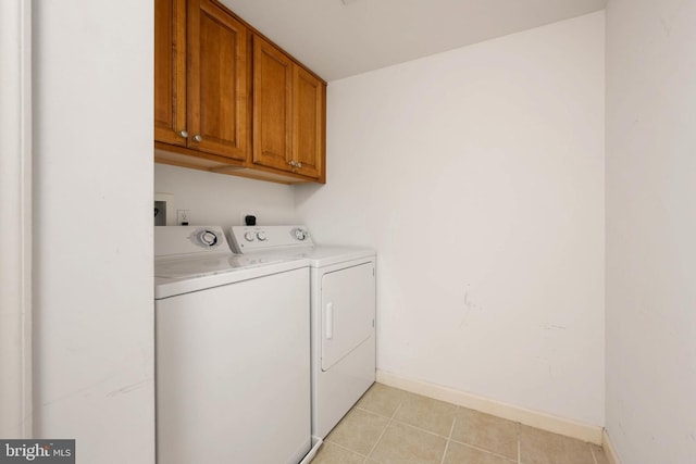 washroom with washing machine and dryer, light tile patterned flooring, and cabinets