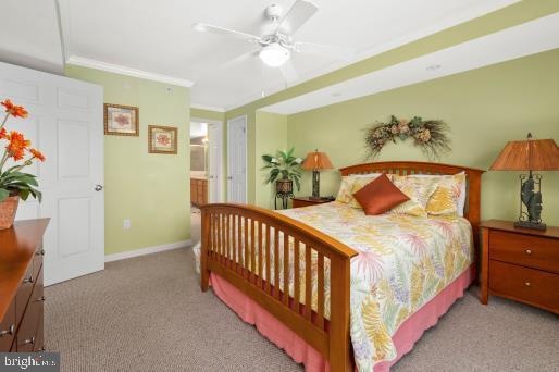 carpeted bedroom featuring ensuite bathroom, ceiling fan, and crown molding