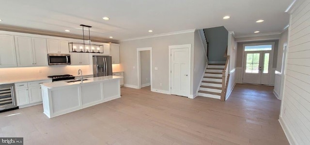 kitchen featuring wine cooler, light hardwood / wood-style floors, an island with sink, stainless steel appliances, and white cabinets