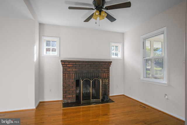 unfurnished living room featuring hardwood / wood-style floors, ceiling fan, and a brick fireplace