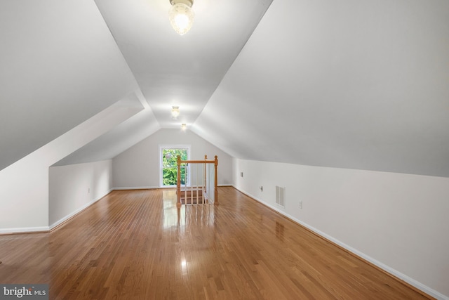 additional living space with hardwood / wood-style floors and lofted ceiling