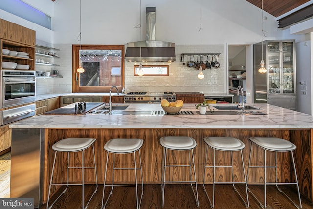 kitchen with light stone countertops, appliances with stainless steel finishes, tasteful backsplash, wall chimney exhaust hood, and dark hardwood / wood-style flooring